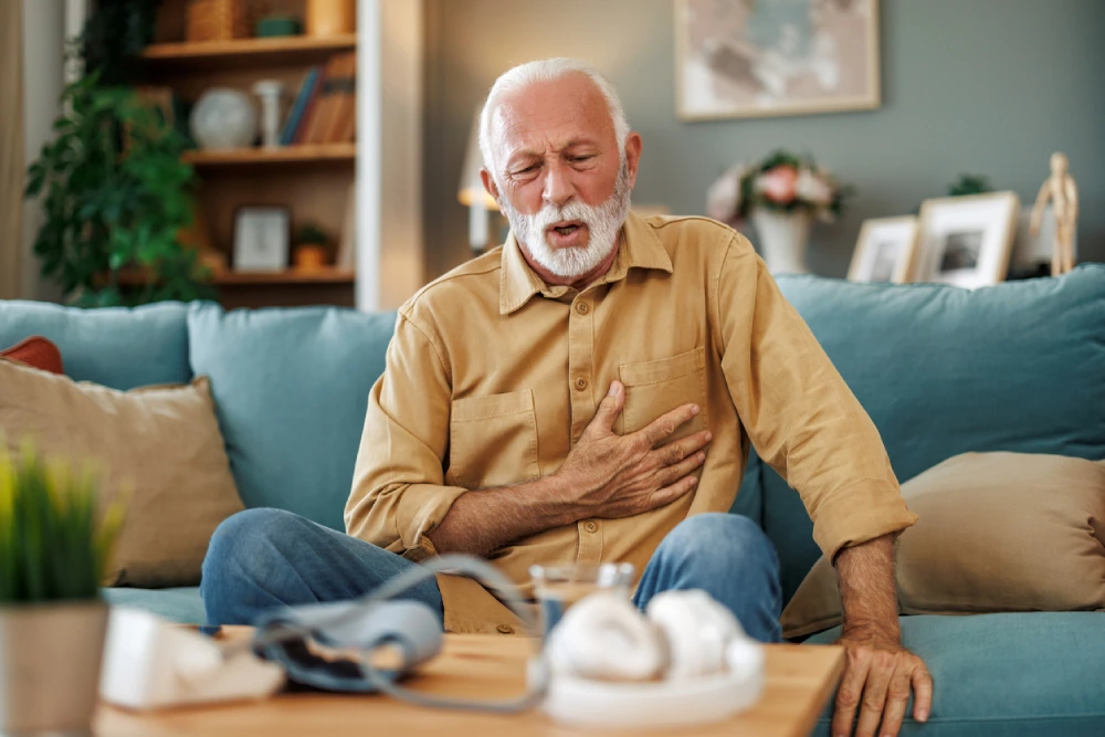 an older male holding his chest, experiencing chest pain, a common hypertension symptom