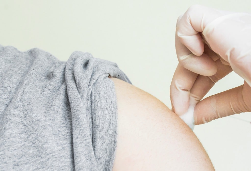 A pharmacist holding a cotton ball to a patients arm following the flu shot