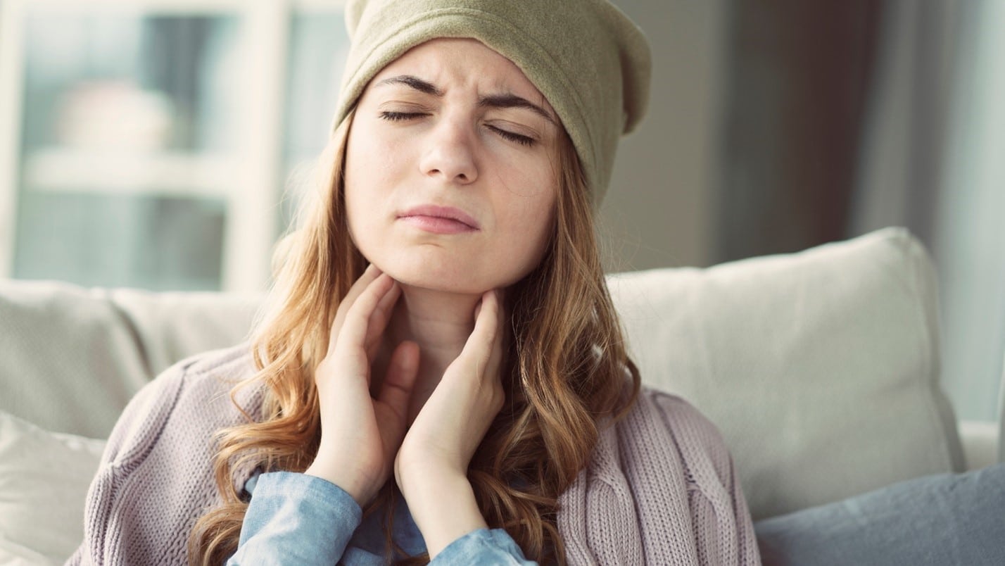 Woman holding her throat with discomfort.