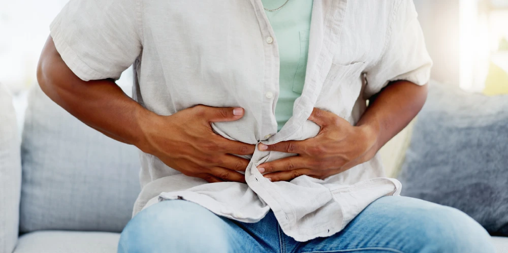 man clutching his stomach suffering from irritable bowel syndrome symptoms