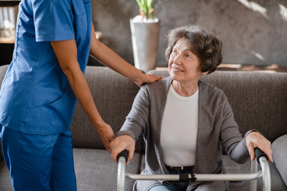 woman with Parkinson's disease looking at a support worker while using a walker as a mobility aid