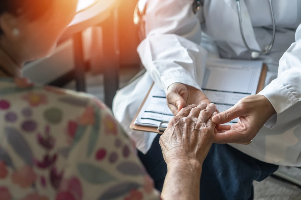 Doctor holding the hand of an elderly women who has Parkinson's disease