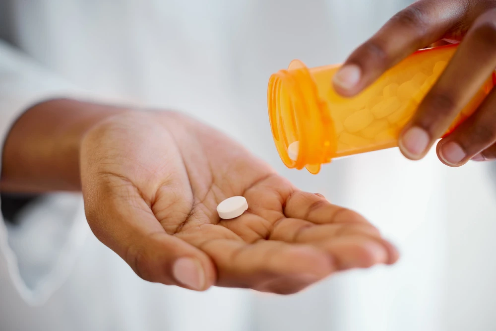 A woman dropping a white pill into her hand to manage her lupus symptoms