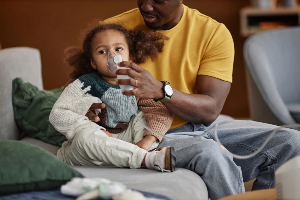 father helping daughter use a nebulizer