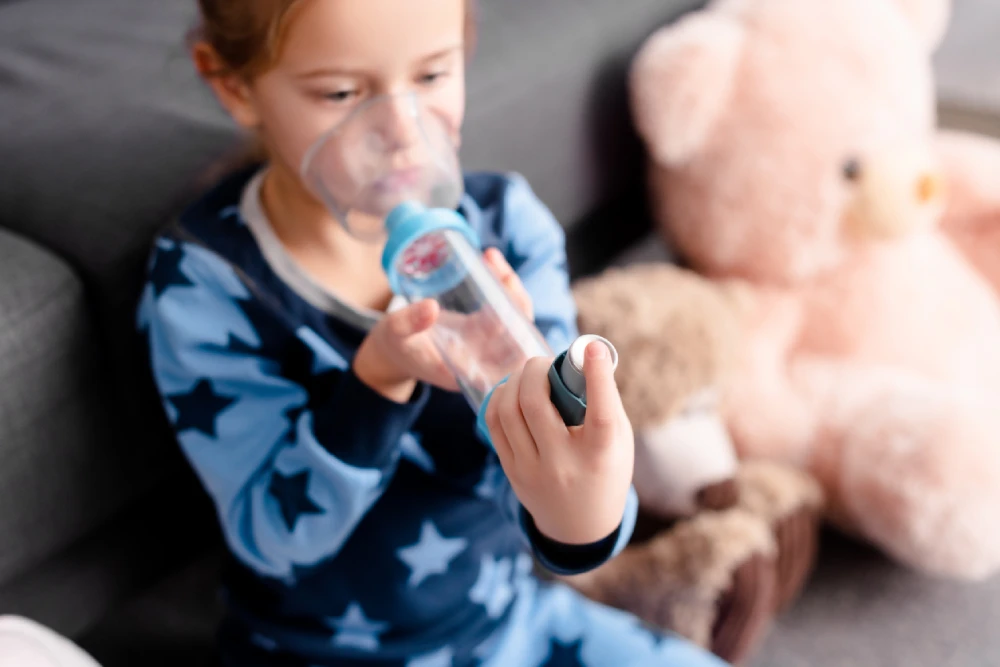 child using an inhaler with a spacer device for asthma management