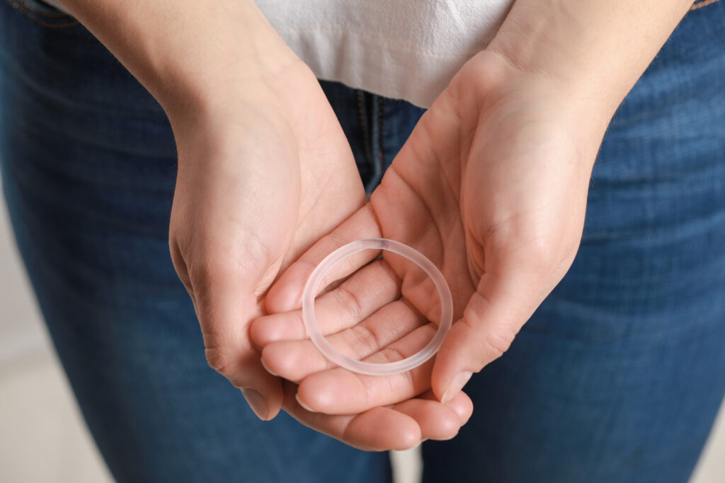 A close-up of a woman's hands holding a vaginal ring. 