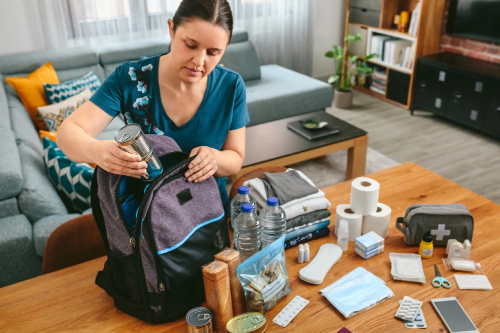 a woman packing a travel first aid kit using a backpack