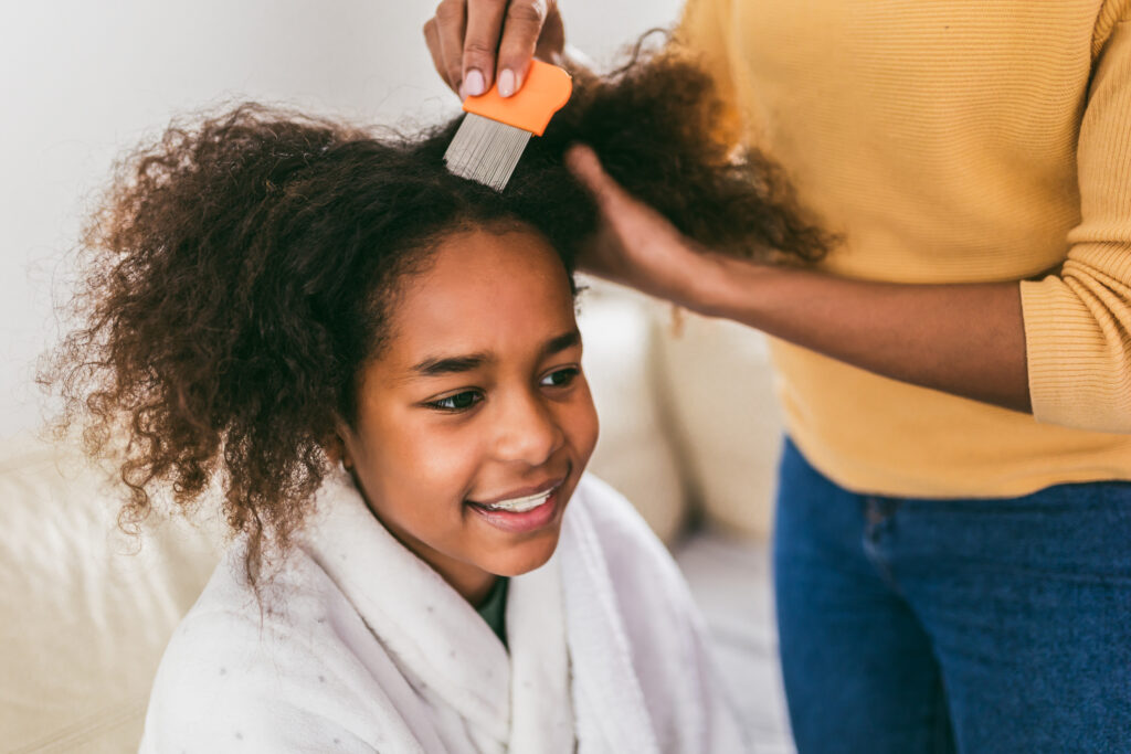 A mother uses a comb to remove lice from her laugher's curly hair. 