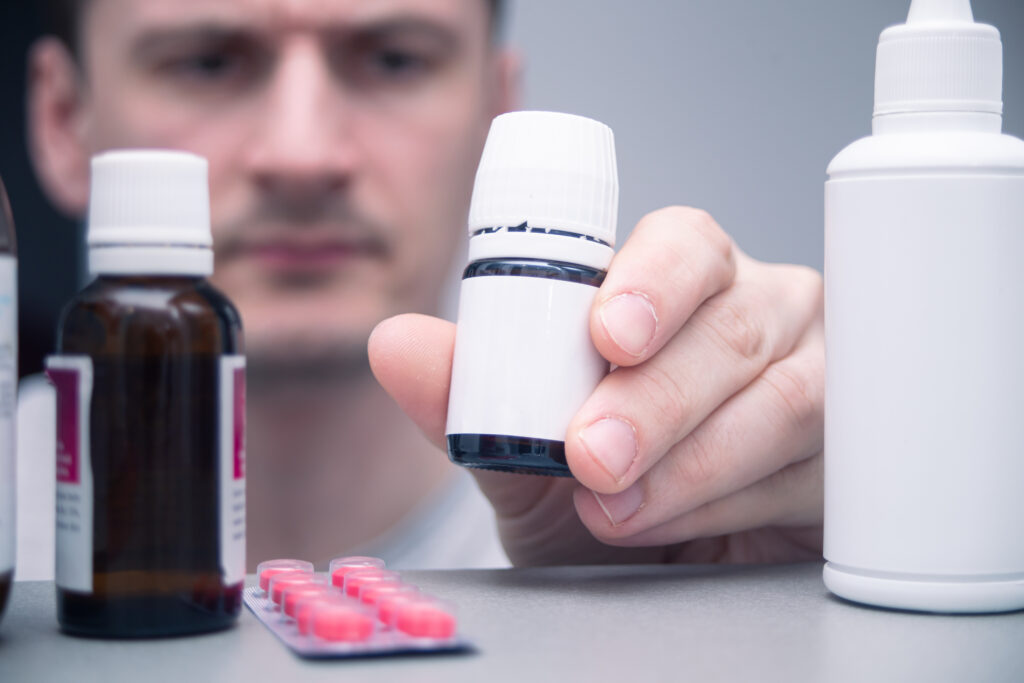 A man takes a medication bottle from his medicine cabinet. 