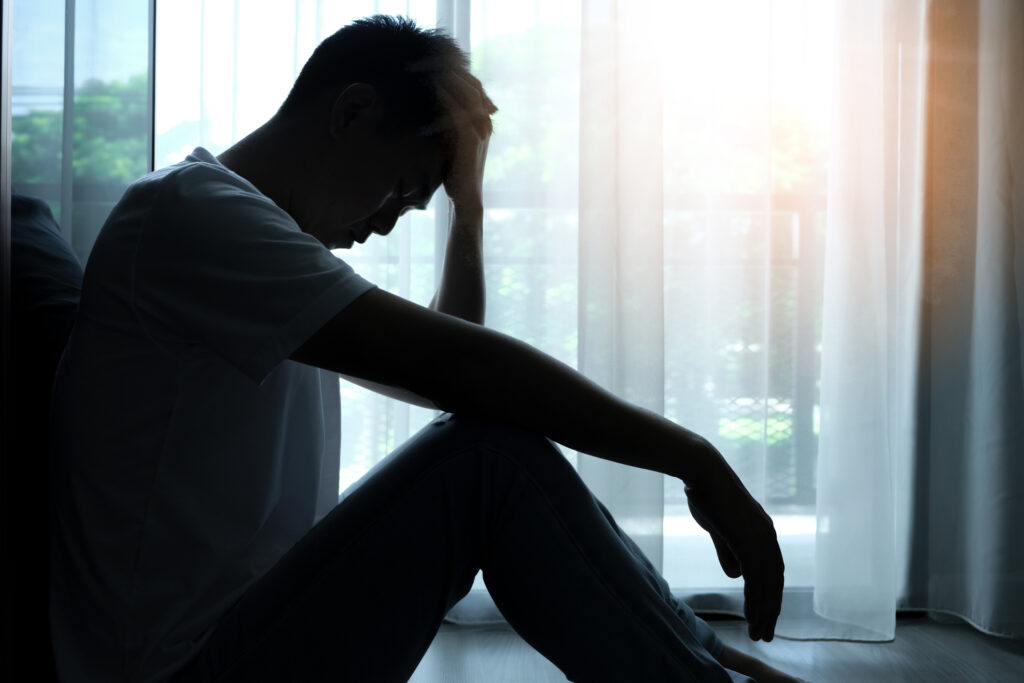 A man sits on the floor in a room holding his head. 