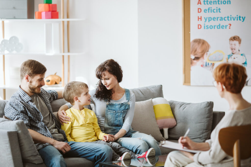 Parents and son sit together at a therapy session with a counselor. 