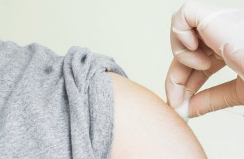 A pharmacist holding a cotton ball to a patients arm following the flu shot