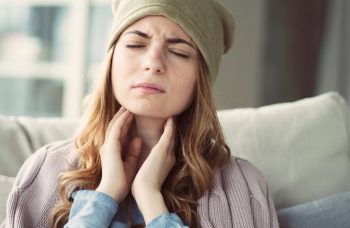 Woman holding her throat with discomfort.